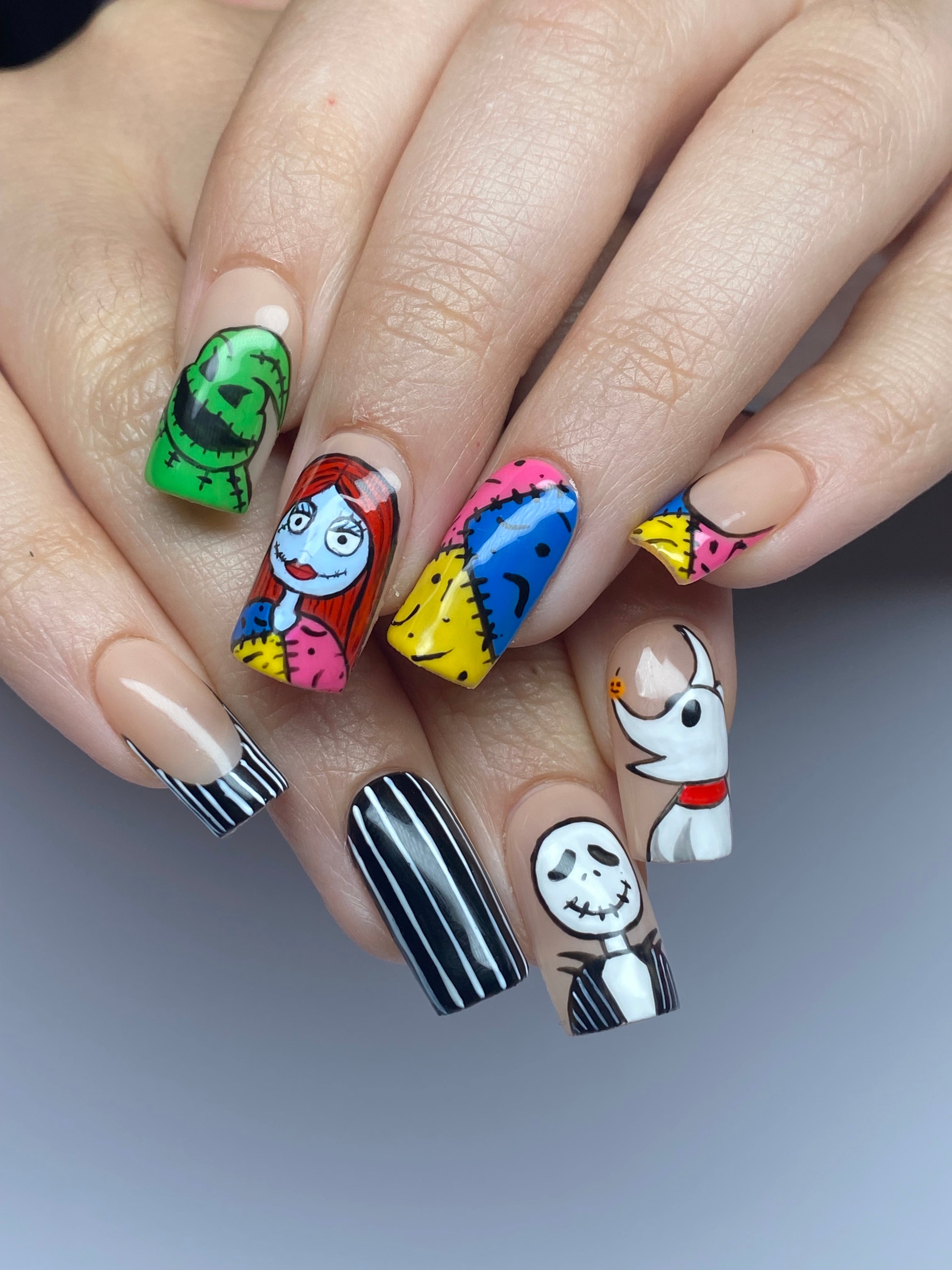 Client hands with short square shaped gel-x extensions with nightmare before christmas hand painted nail art.
