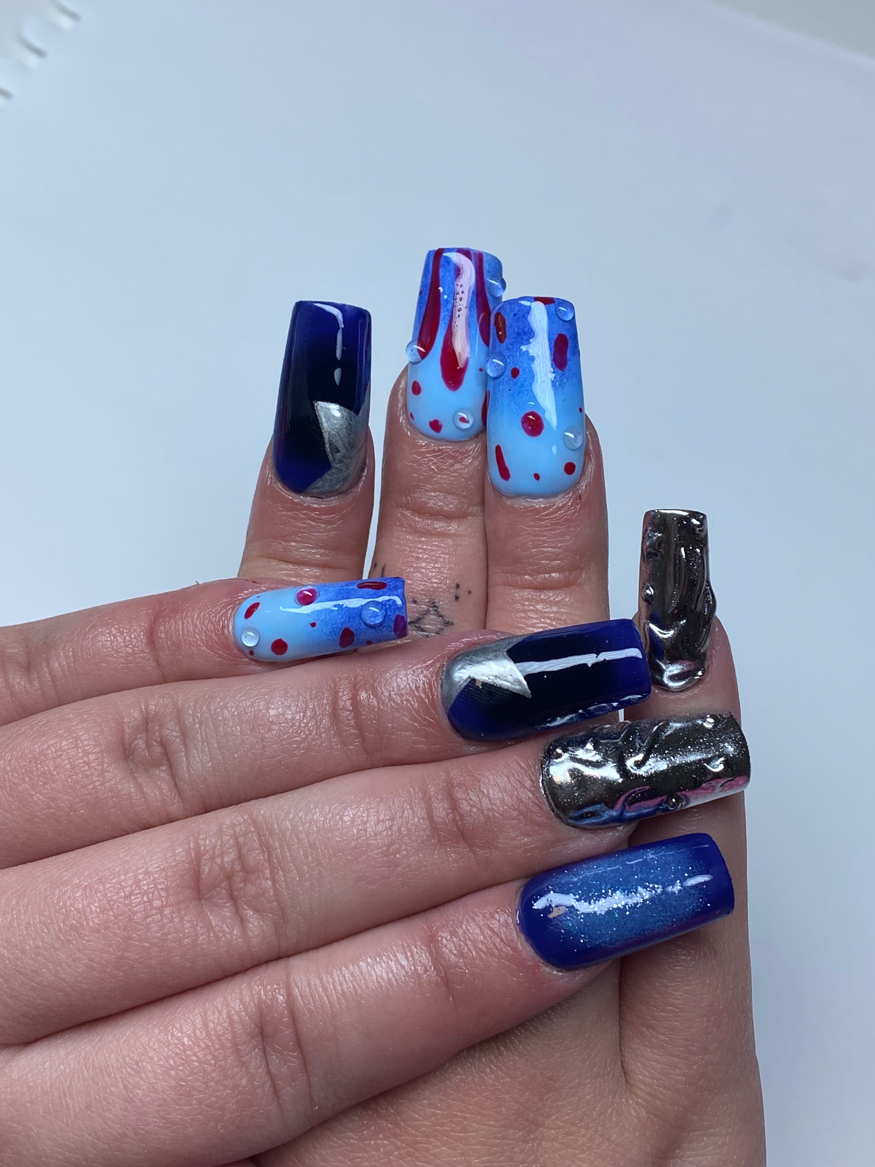 Client hands with medium gel-x extensions with dark blue hand painted nail art.