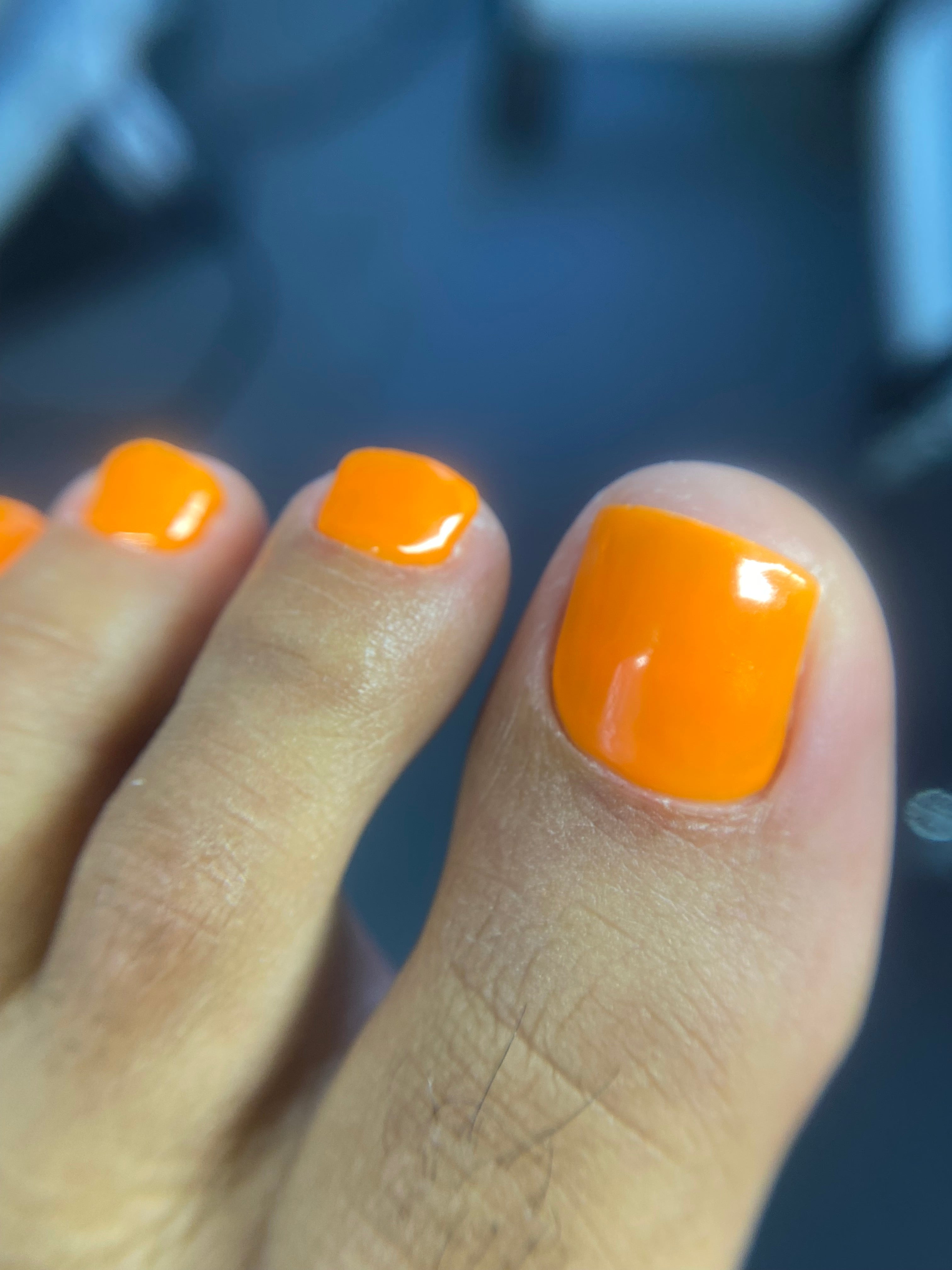 Luxury dry e-file pedicure with clean cuticle work & orange gel polish finish.