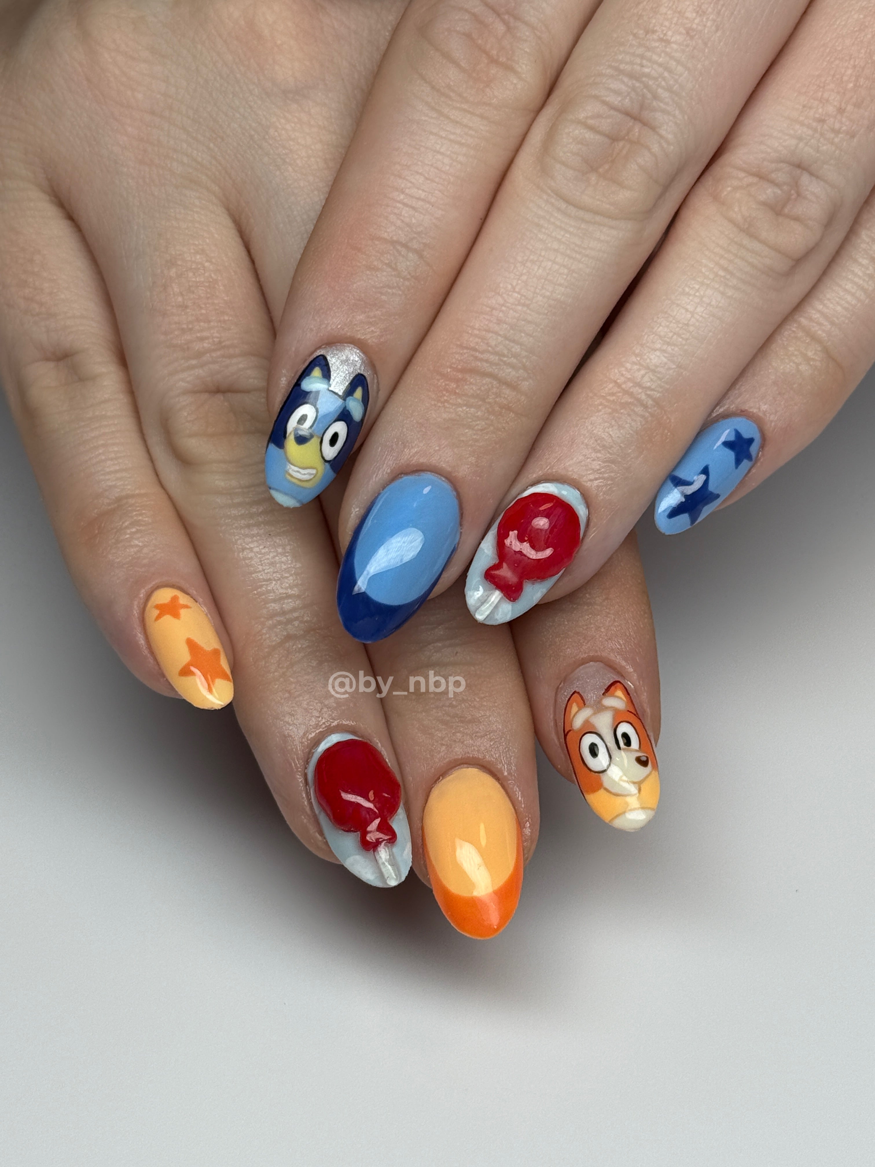 Client hands with short almond gel-x extensions with hand painted bluey & bingo nail art.