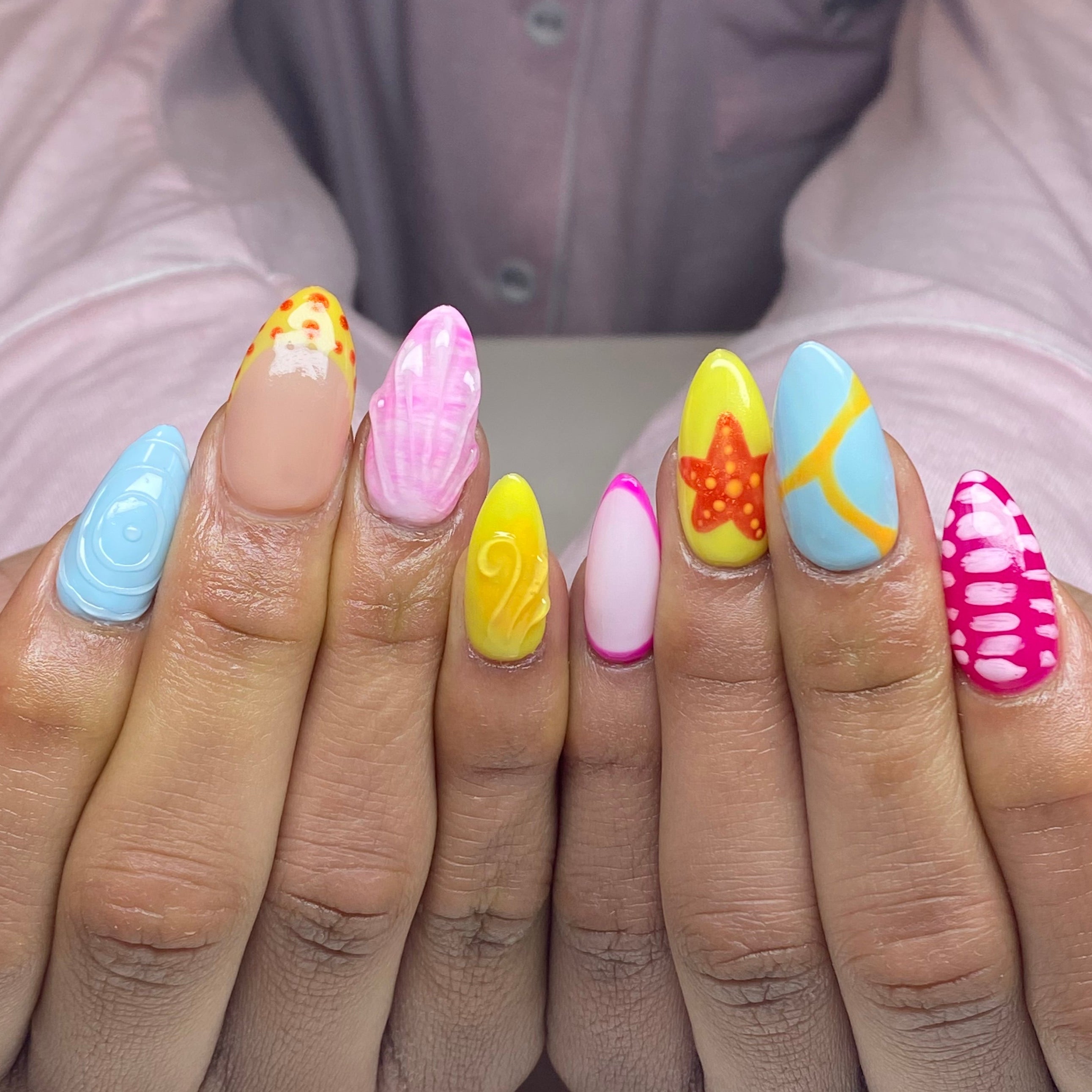 Client hands with medium almond Apres gel-x extensions with bright coloured nail art.