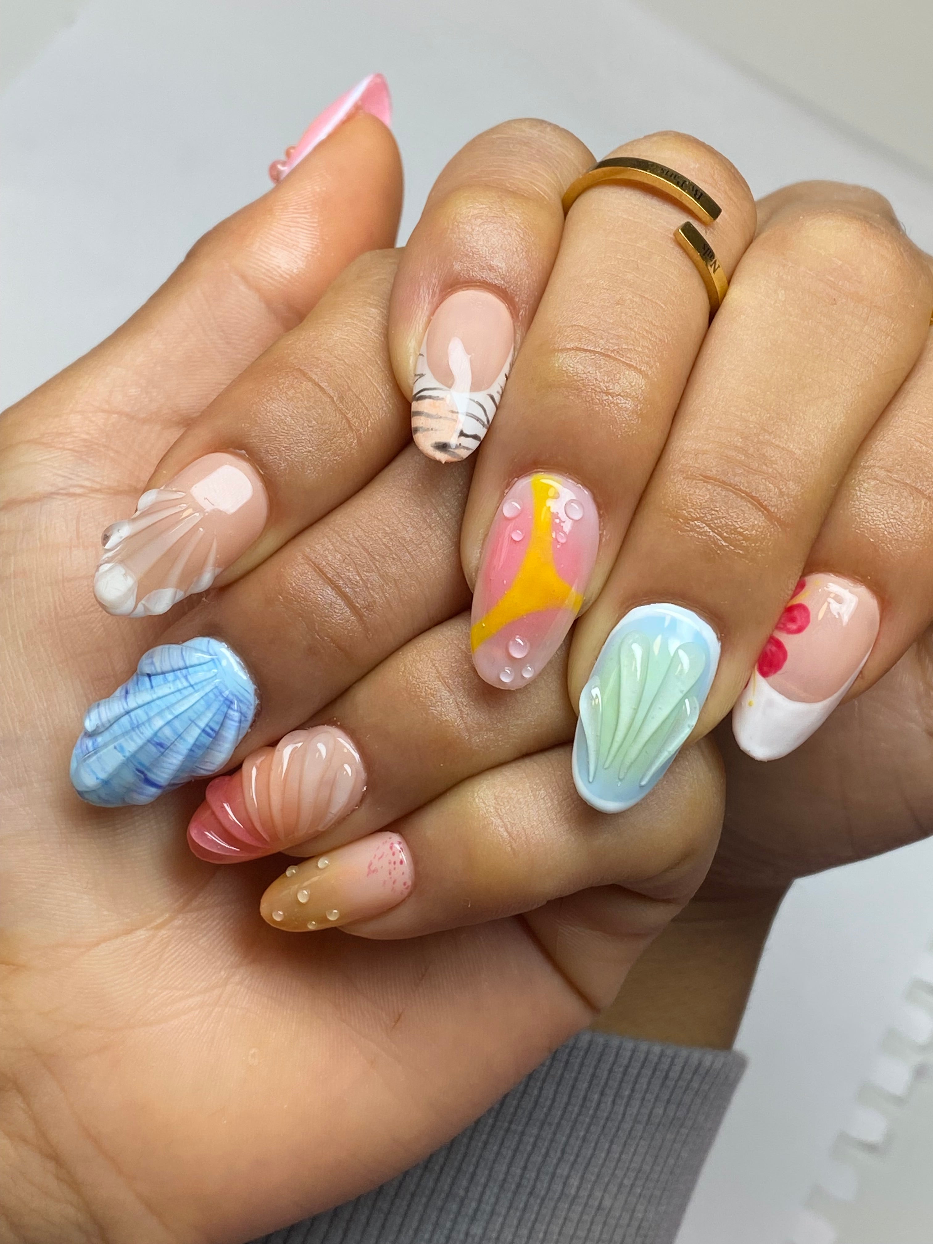 Client hands with short round gel-x extensions with summer inspired hand painted nail art.